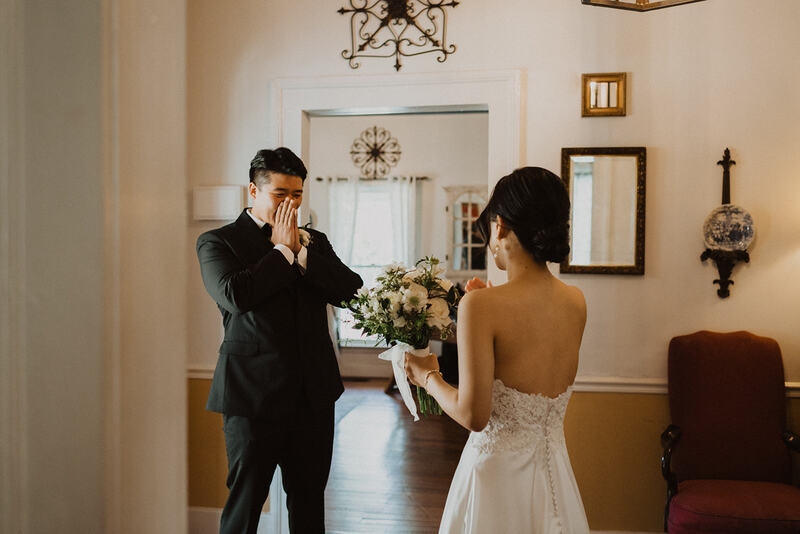 groom reacts to bride during first look in farmhouse wedding venue foyer