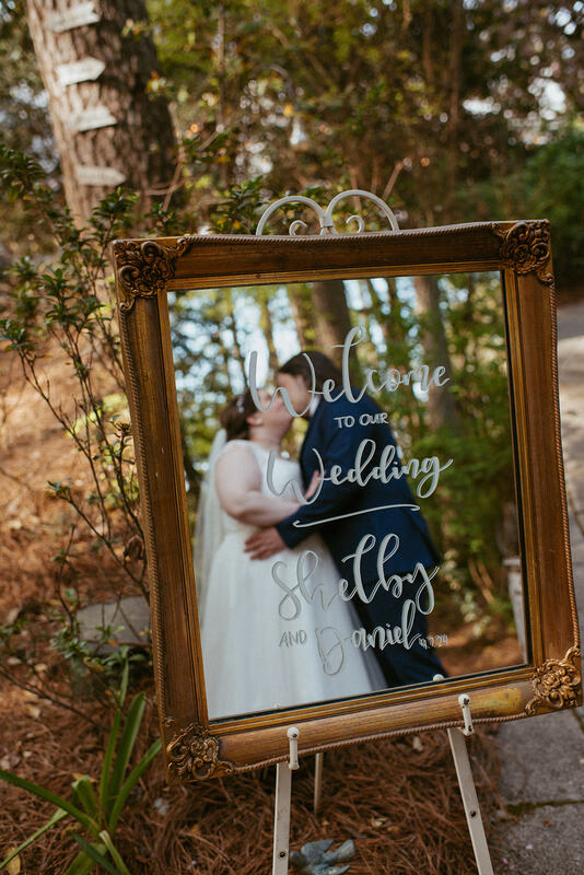 welcoming mirror sign with bride and groom kissing in reflection
