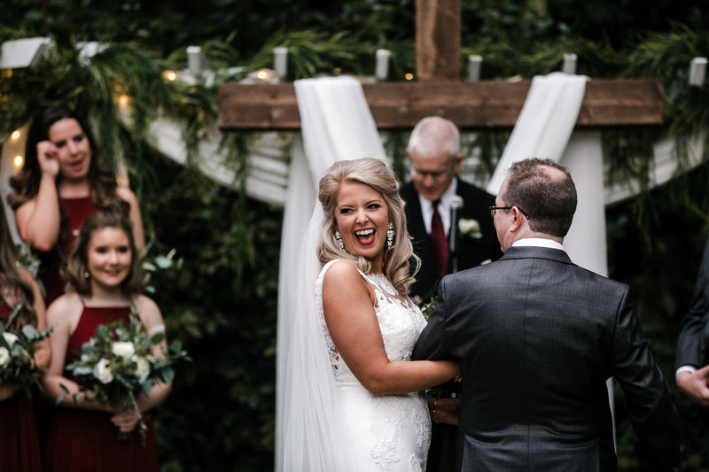 bride laughs as dad hands her off during outdoor ceremony
