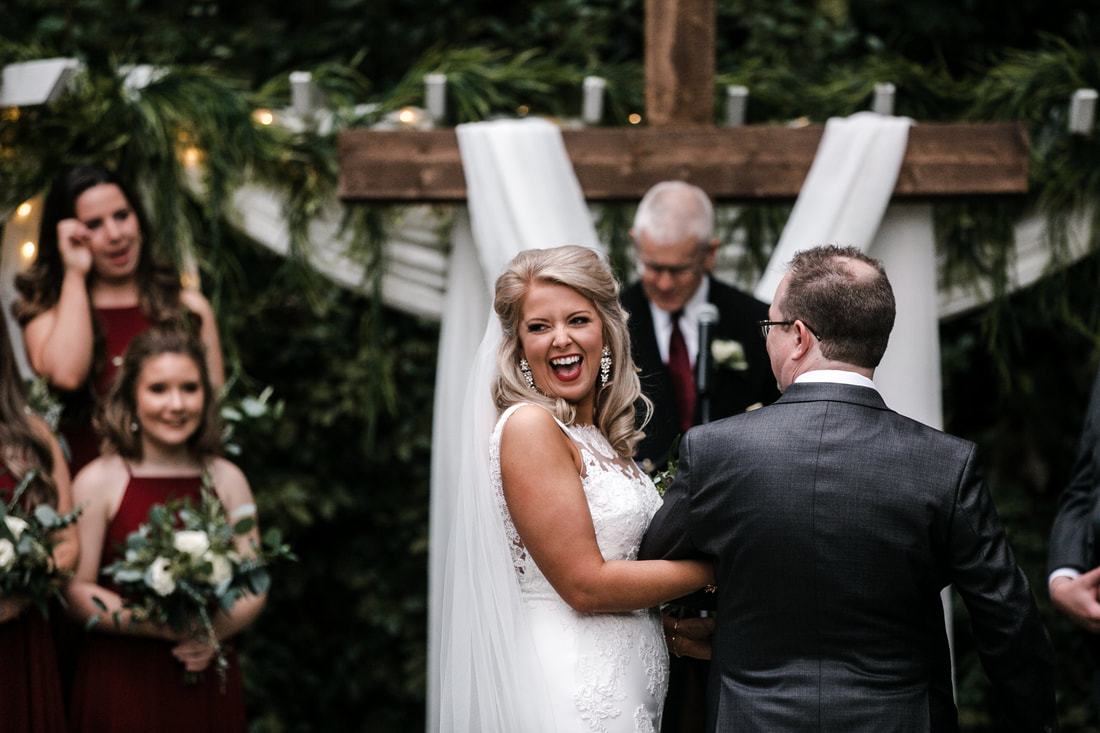 bride smiling at garden ceremony with cross in background