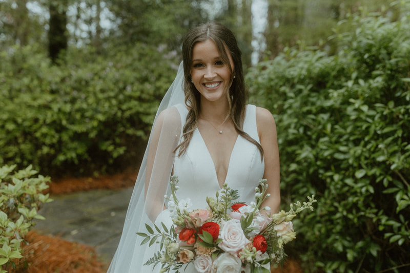 bride with white, blush, and red bouquet