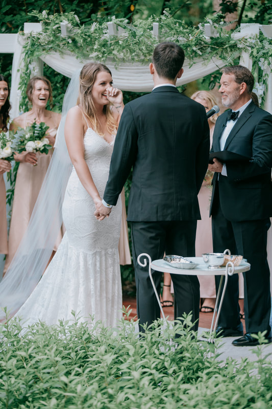 bride laughing at altar decorated with greenery