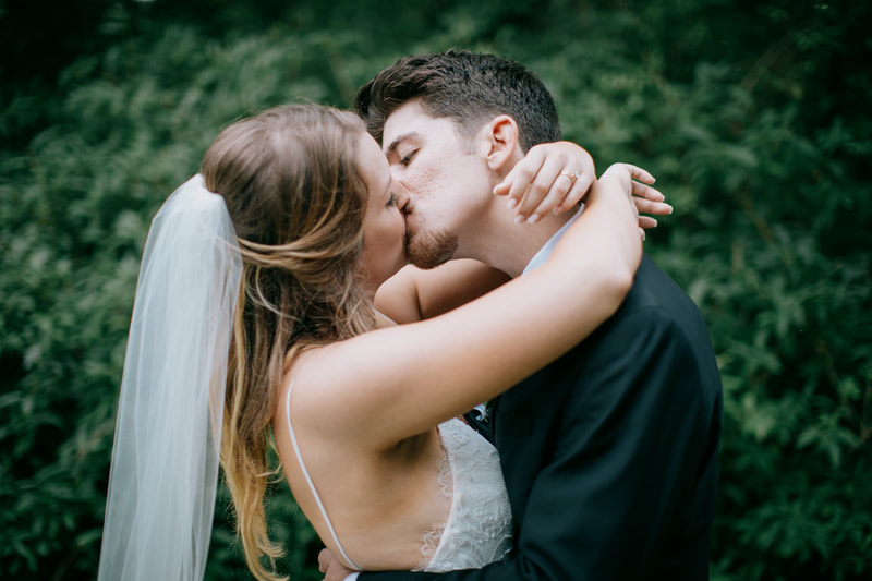 newlyweds kiss in green Four Oaks' gardens in july