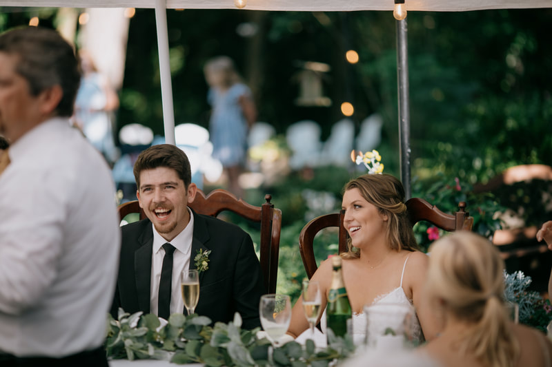 couple laughing during toasts at july reception