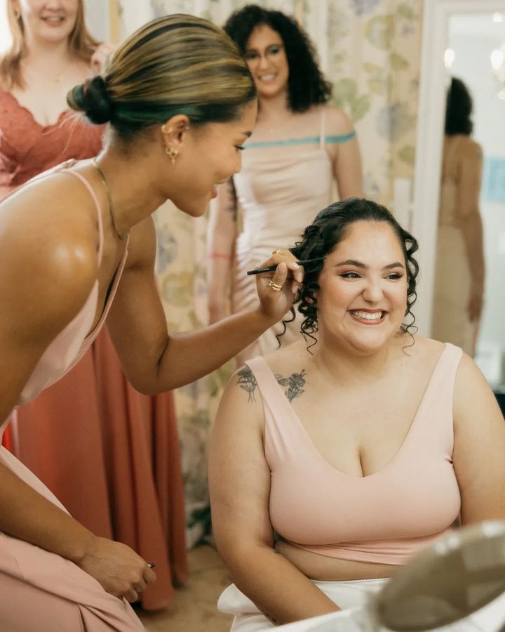Bridesmaid applying makeup to bride pre ceremony