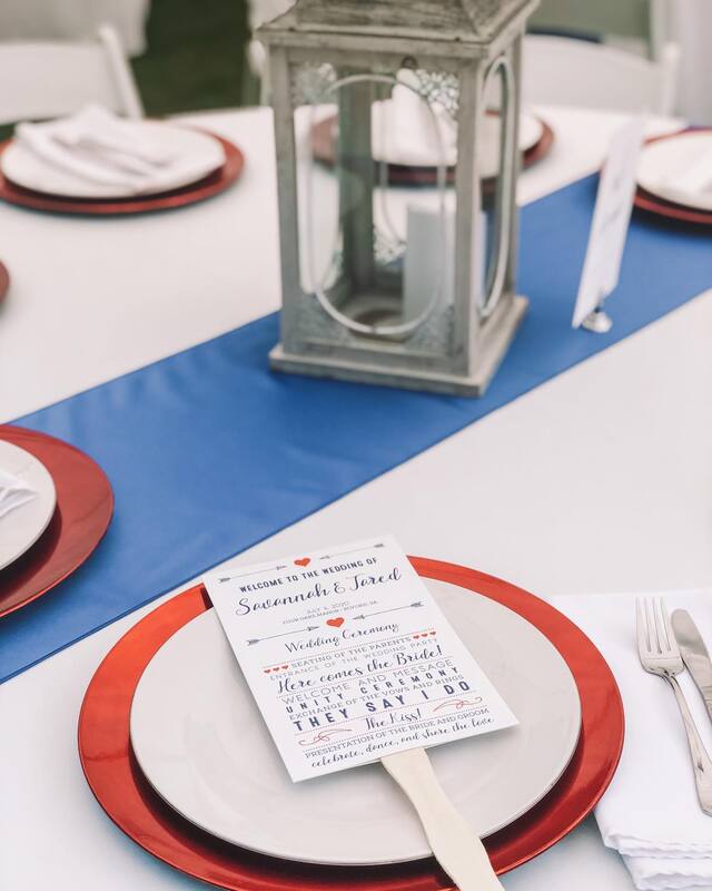 white table with blue runner and red chargers