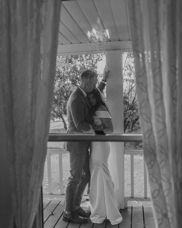 Window view of bride & groom at farmhouse wedding venue