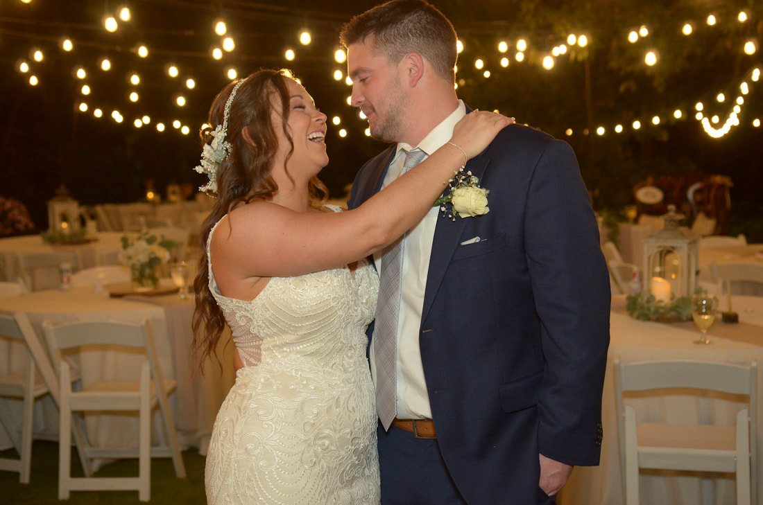 couple holding each other and smiling under reception lights