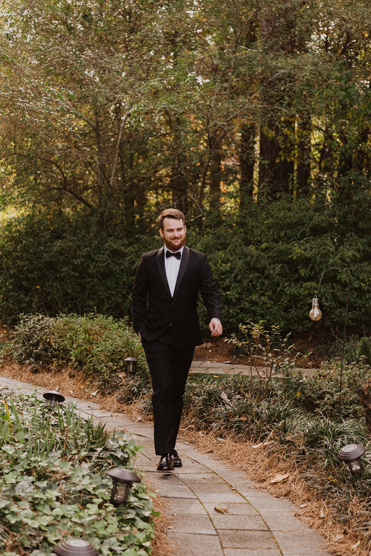 groom walking through fall garden venue