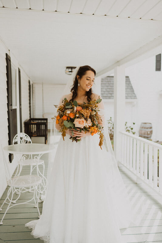 bride with fall bouquet posing on farmhouse porch