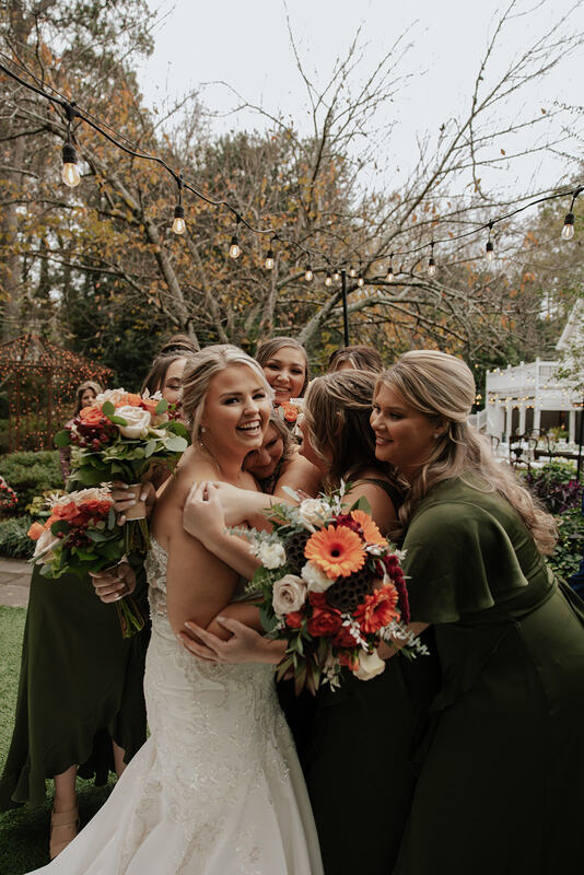 bridesmaids hugging bride at garden venue