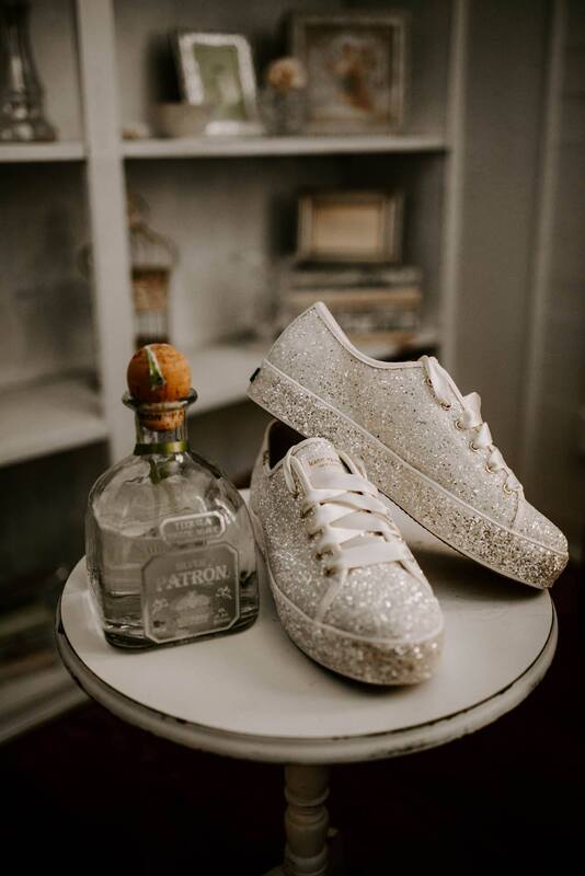 bride's glittery white sneakers on table with perfume