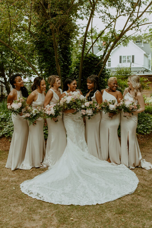 bride and bridesmaids in satin champagned dresses posing in garden venue