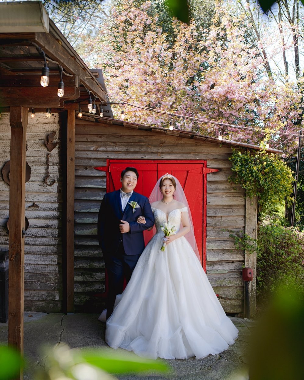 asian bride and groom by red doors
