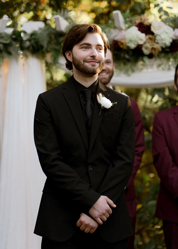 groom in all black standing at altar during processional