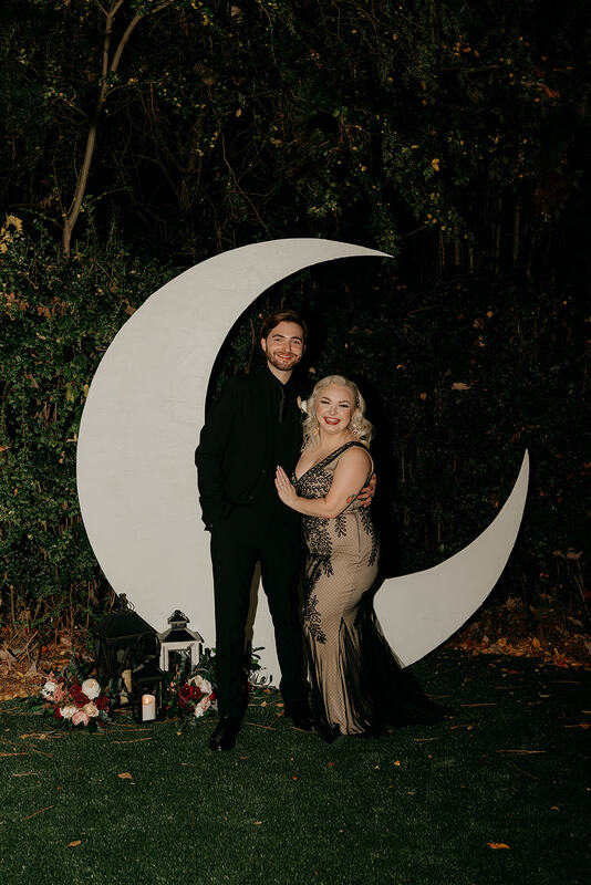 bride and groom posing in front of moon photo backdrop