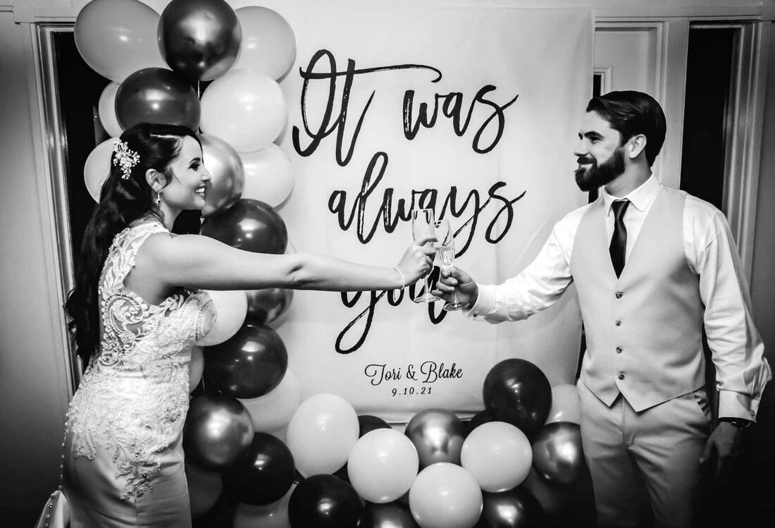 bride and groom toasting in front of photo booth backdrop