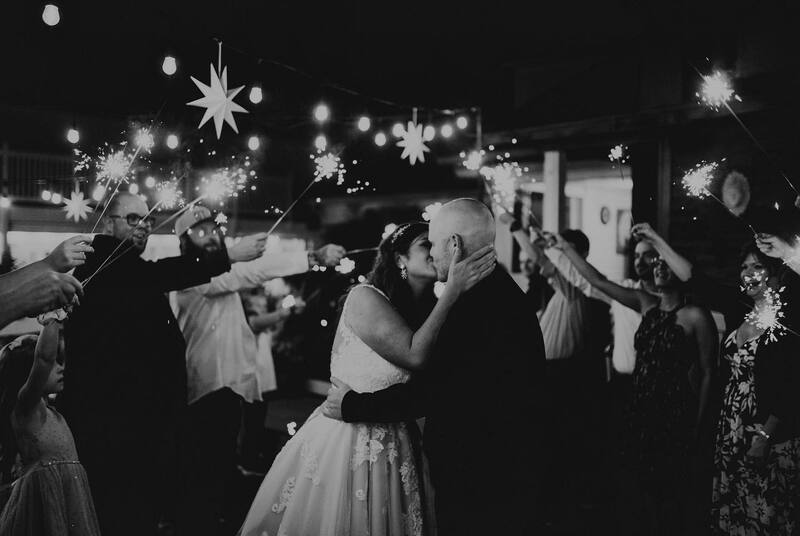 black and white photo of bride and groom kissing during sparkler grand exit
