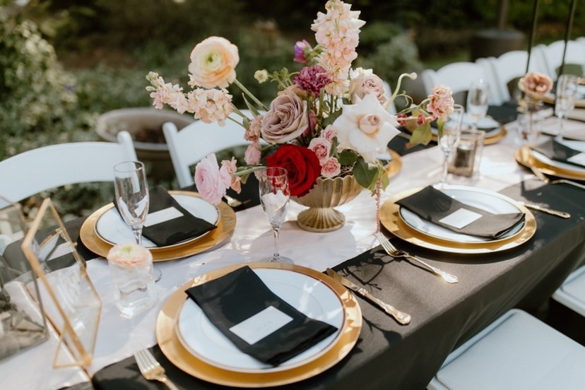 Banquet-style reception tables with black and gold decor and floral arrangements