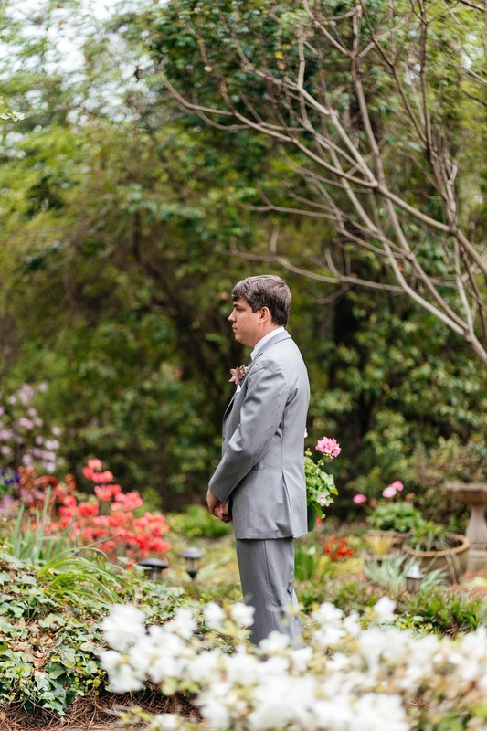 groom standing in garden venue before first look