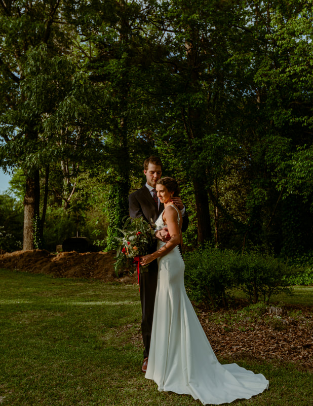 bride and groom posing in garden venue with trees in background