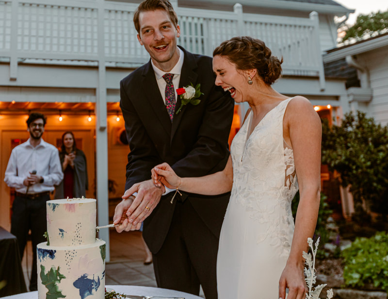bride laughing during cake cutting at outdoor wedding reception