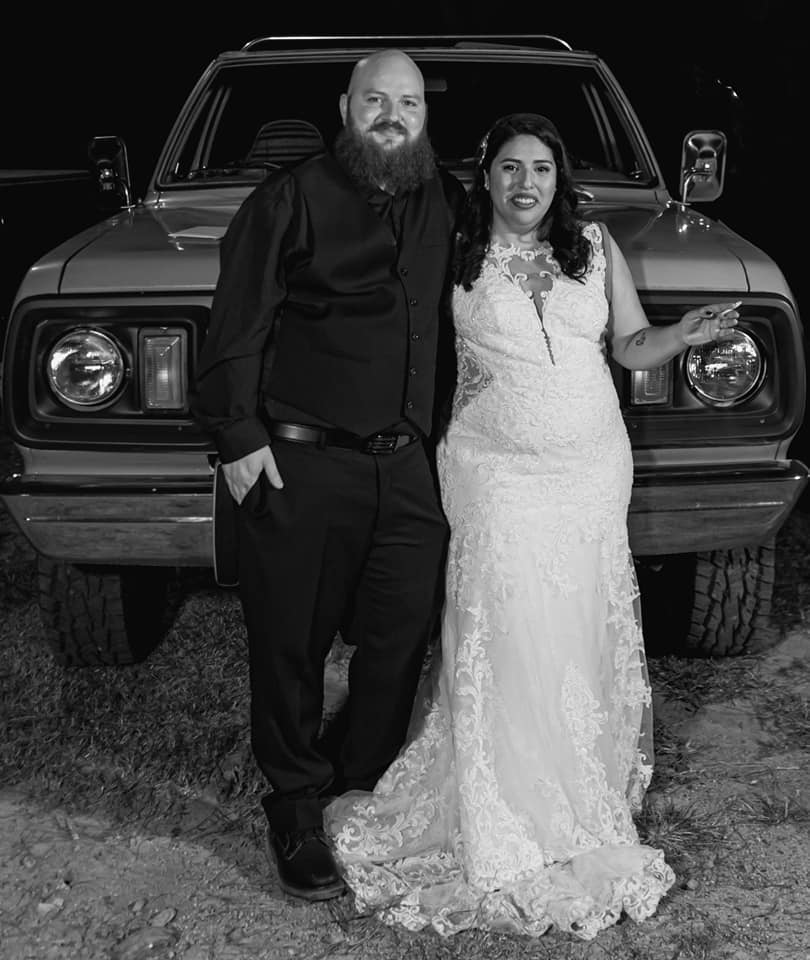 black and white photo of bride and groom in front of vintage truck
