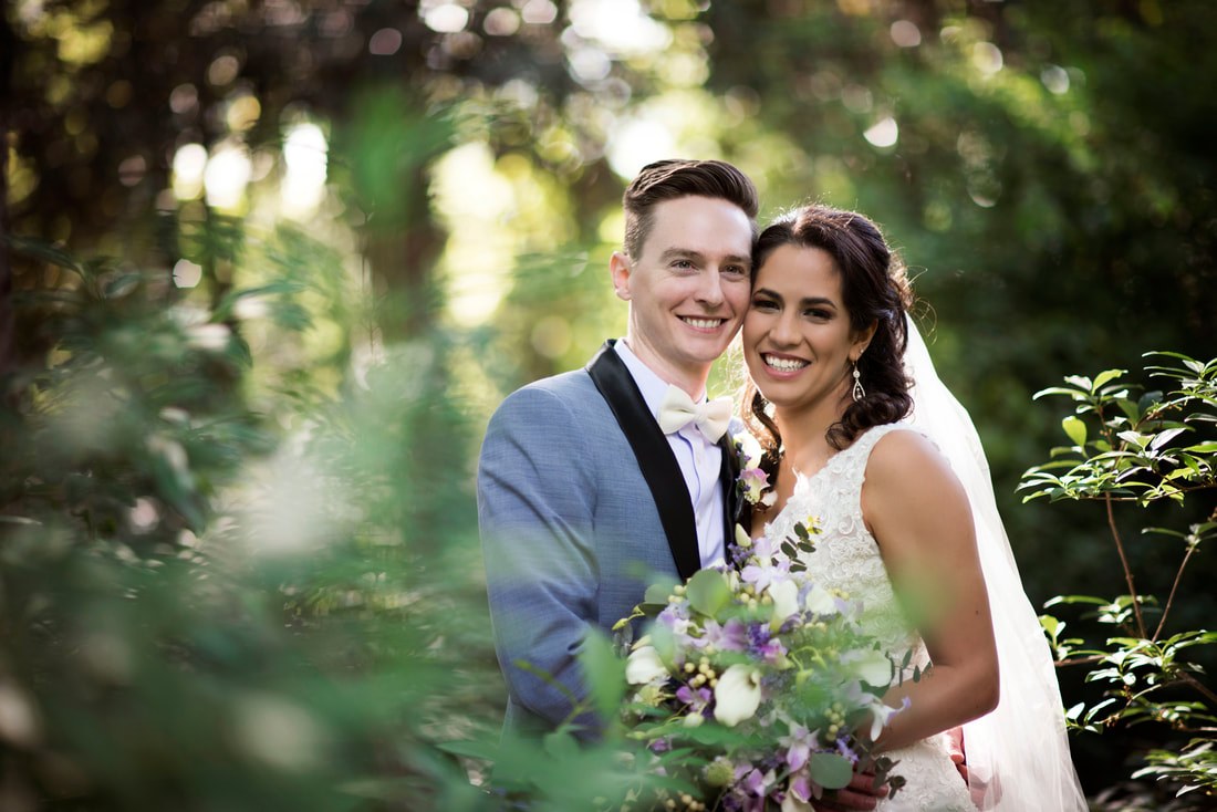 bride and groom standing in garden venue surrounded by plants