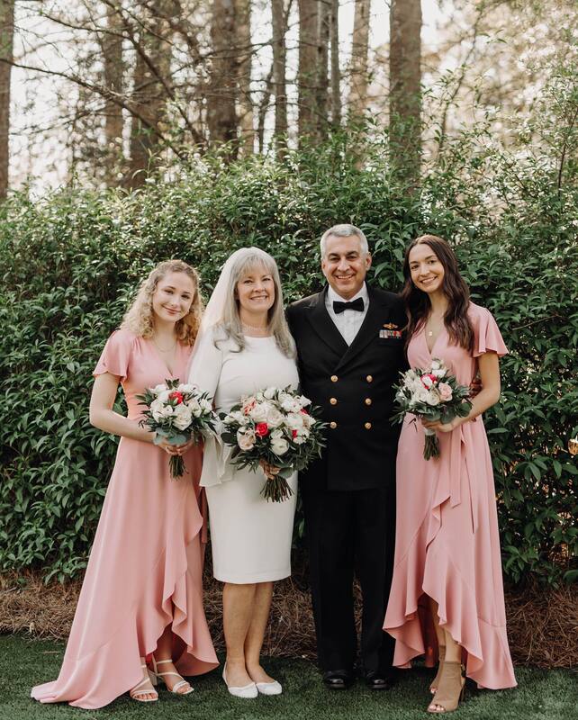 bride, groom, and daughter bridesmaids in front of green bush