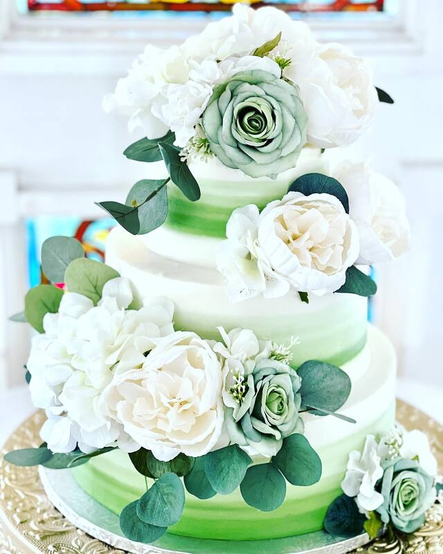 3-tier cake with ombre green frosting and white and sage fake florals