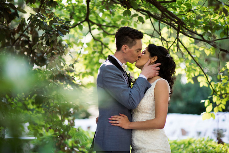 bride and groom kissing under garden tree