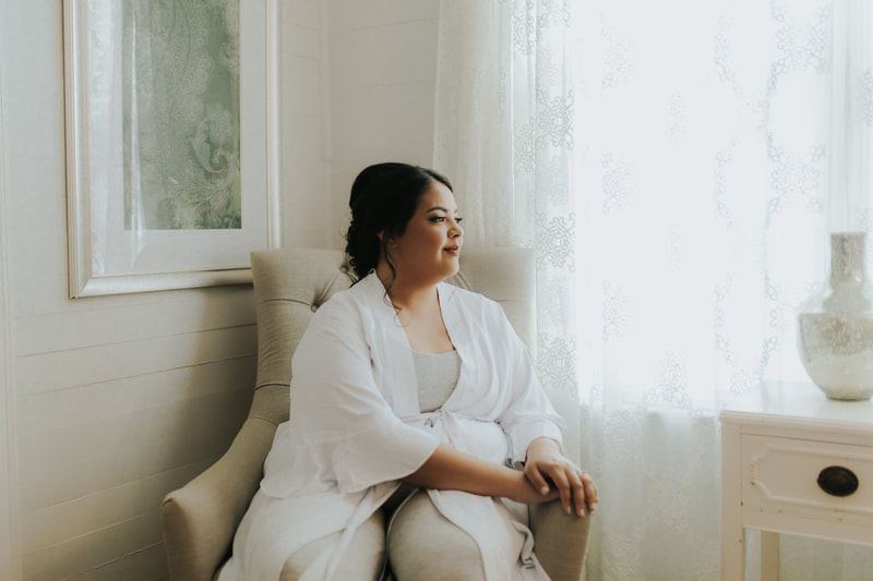 bride in white robe sitting on farmhouse chair