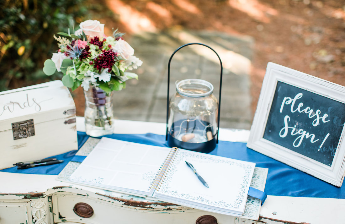 White, rustic guestbook table with chalkboard sign, a white box for cards, and flowers.