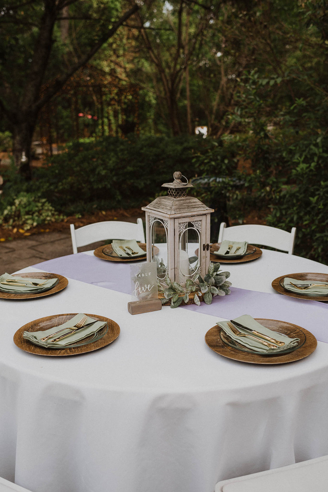 Rustic spring tablescape with wood chargers and lantern plus sage green and lilac linens