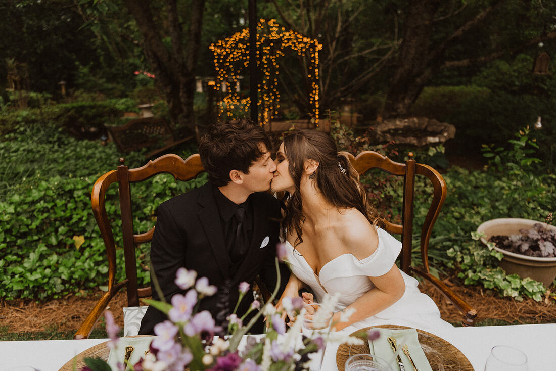 couple kissing at lavender and sage head table