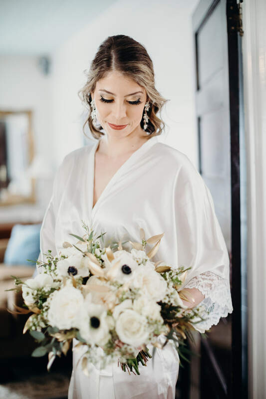 bride in silk robe holding bouquet with champagne dyed greenery
