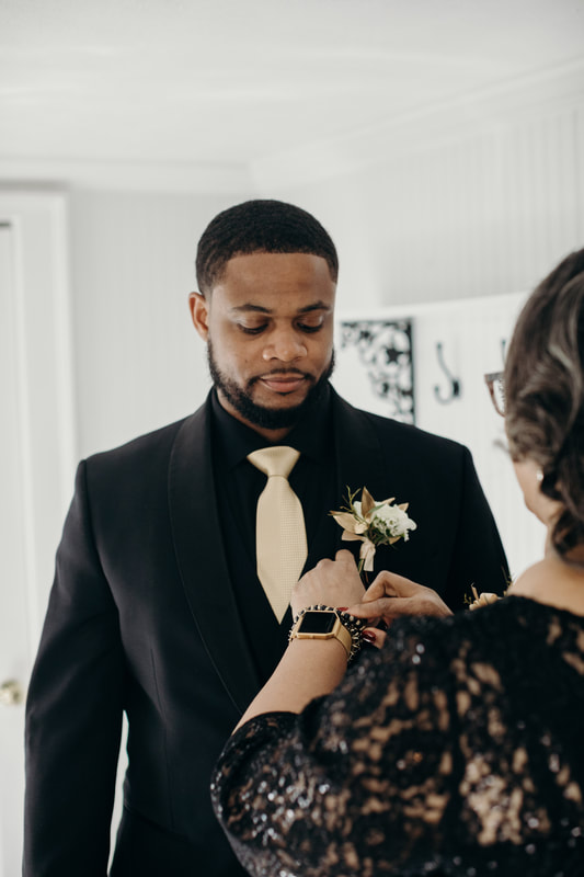 mother pinning boutonniere on groom