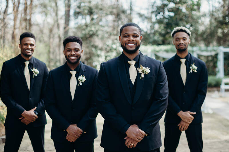 groom and groomsmen in matching black suits with champagne-colored ties and boutonnieres