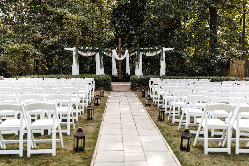 Outdoor fall ceremony with lantern pew markers and cross at altar