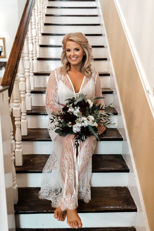 bride in lace robe siting on farmhouse steps