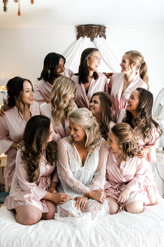 bride with bridal party in light pink robes in Four Oaks bridal bedroom