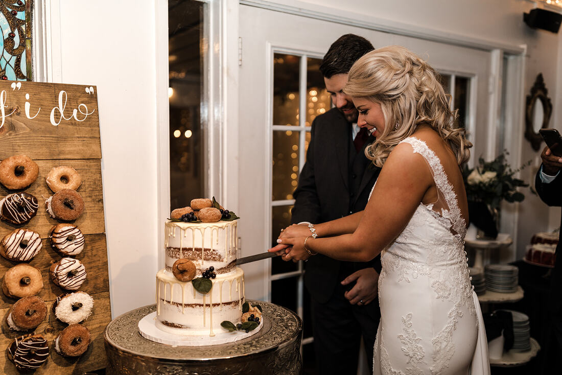 cake cutting ceremony with two-tiered cake decorated with donuts