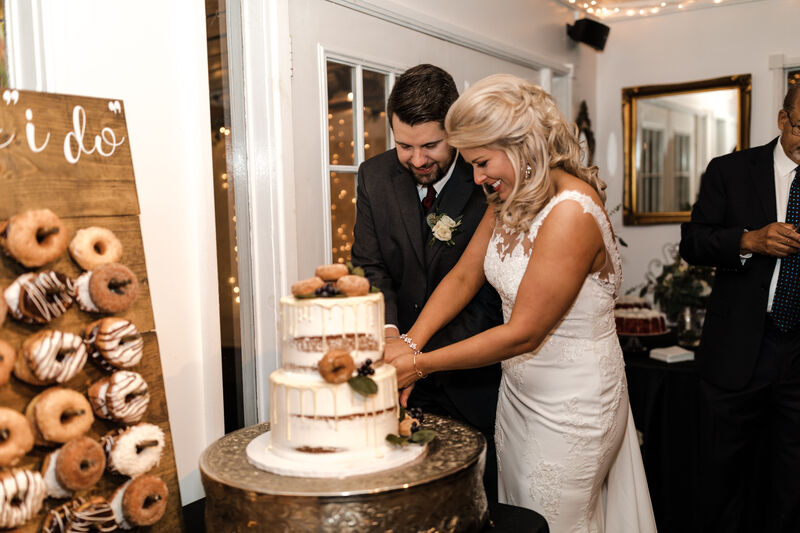 bride and groom cutting cake covered with donuts