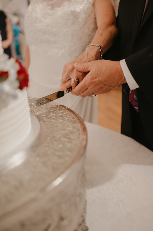 closeup photo of bride and groom cutting wedding cake