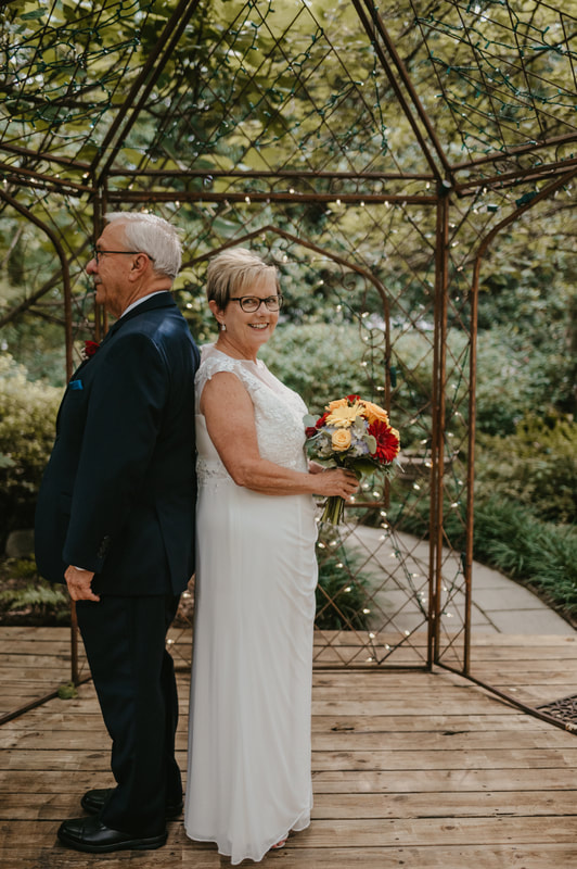 older couple standing back to back for wedding photos