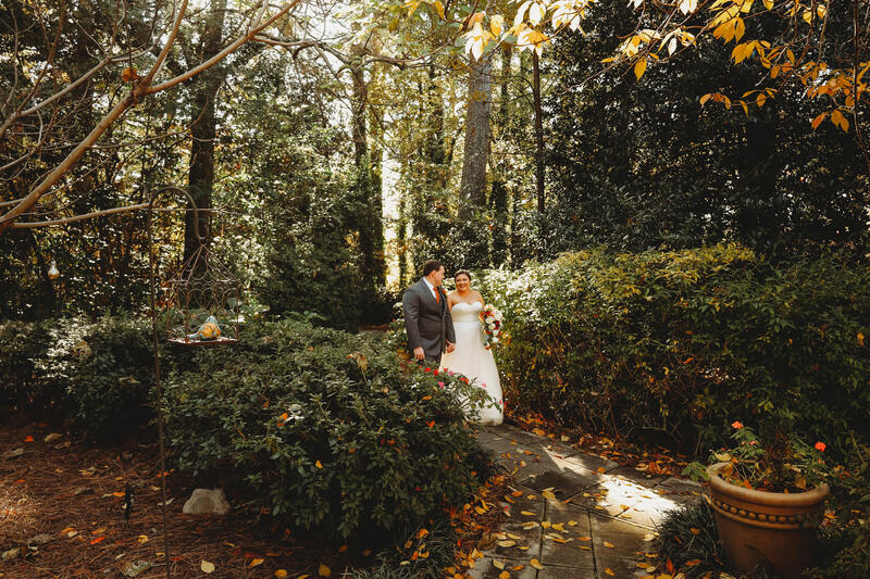 bride and groom walking through path at garden wedding in the fall