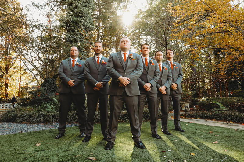 groomsmen in matching charcoal suits with burnt orange details