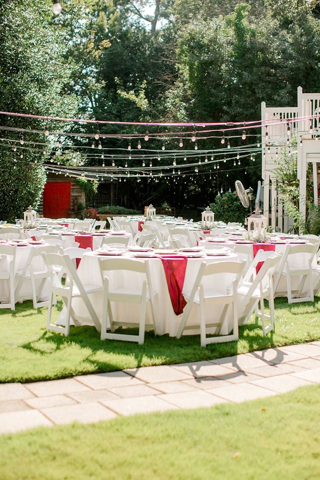 white and red reception tables under string light bulbs