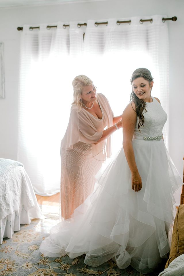 mother-of-the-bride helping button bride's wedding dress