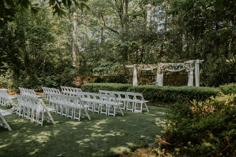 garden wedding ceremony with white wedding chairs